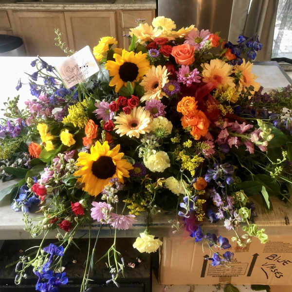 Large mixed flower arrangement with sunflowers, roses, and daisies on a table
