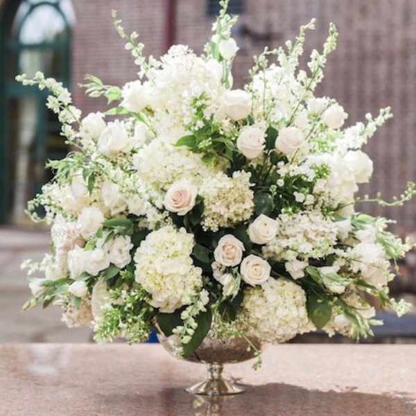 Large white floral arrangement in a silver pedestal bowl