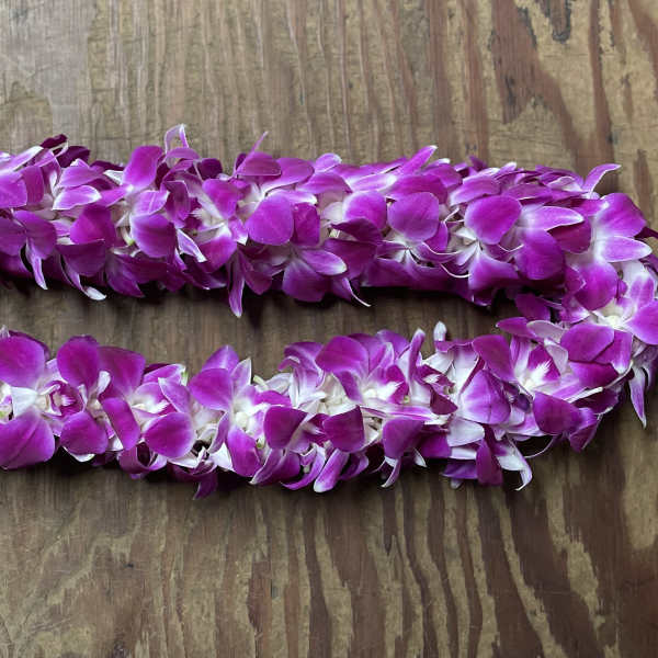 Two purple orchid leis on a wooden surface