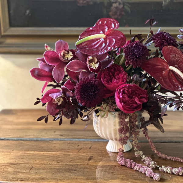 Magenta floral arrangement in a white vase with trailing blooms