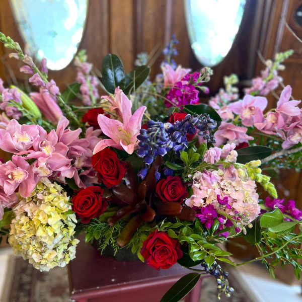Mixed bouquet with pink orchids, red roses, and blue flowers in a vase