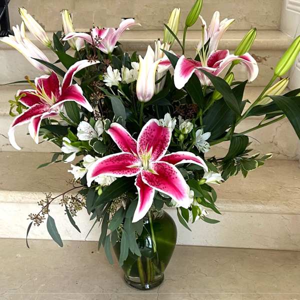 Pink and white lilies arranged in a glass vase