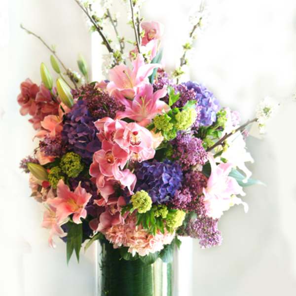 Tall bouquet of pink lilies and purple hydrangeas in a glass vase