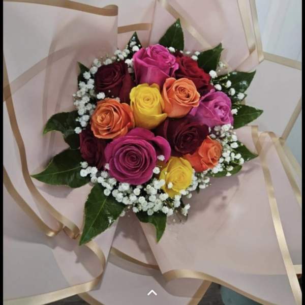 Bouquet of multicolored roses wrapped in pale pink paper