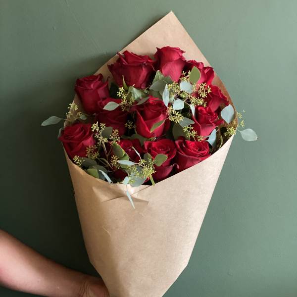 Hand-tied bouquet of red roses wrapped in brown paper