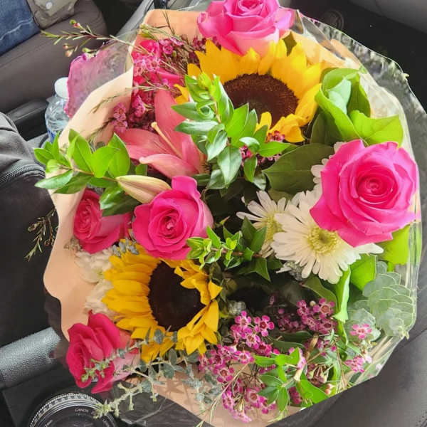 Bouquet of pink roses, sunflowers, lilies, and white daisies