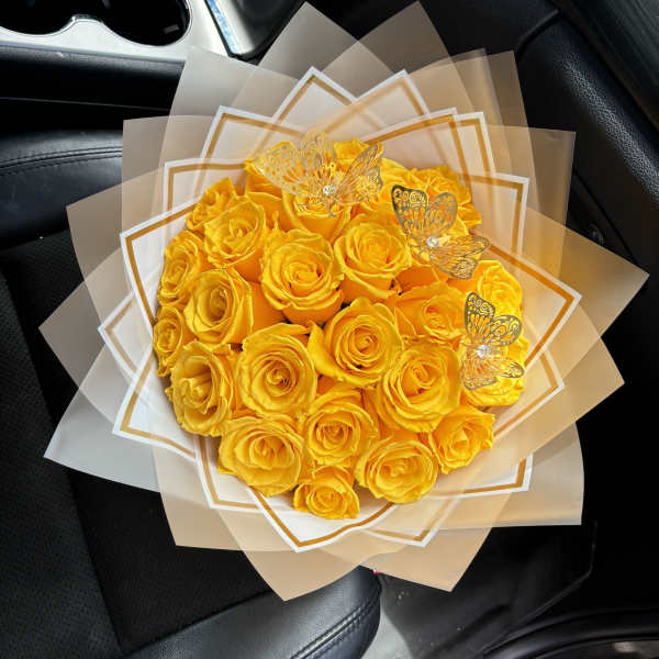 Bouquet of yellow roses wrapped in translucent paper with butterfly accents