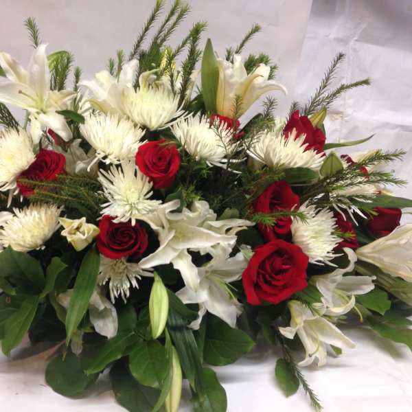 Red roses and white lilies arranged with white spider mums.