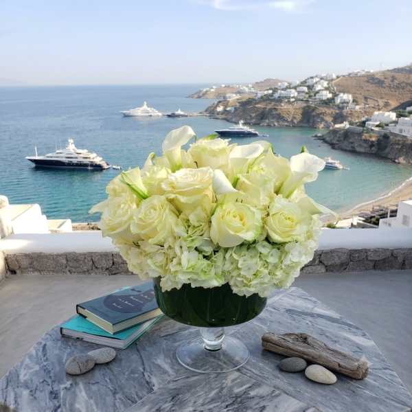 White rose and calla lily arrangement in a glass bowl on a table