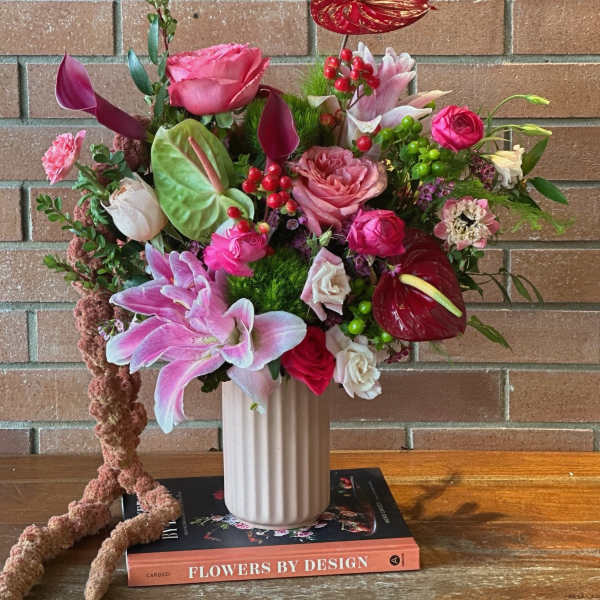 Mixed pink and red floral arrangement in a white vase