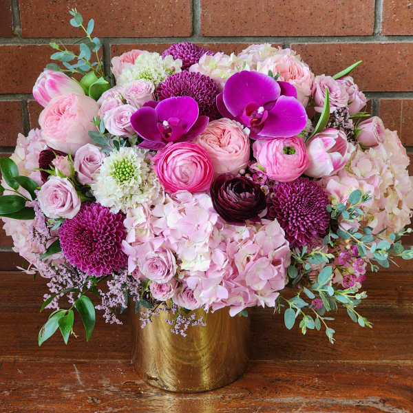 Pink and purple floral arrangement in a gold vase
