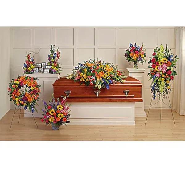 Colorful funeral casket spray with standing floral arrangements