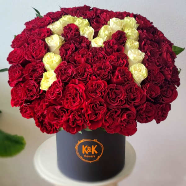Red and cream roses arranged in a black hat box