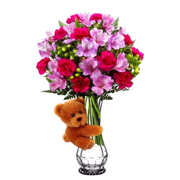 Pink and red bouquet in a clear vase with a teddy bear attached