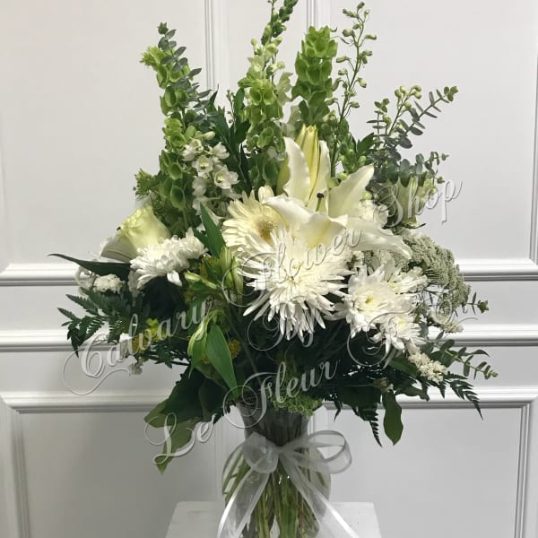 White lilies and daisies in a glass vase with a ribbon bow