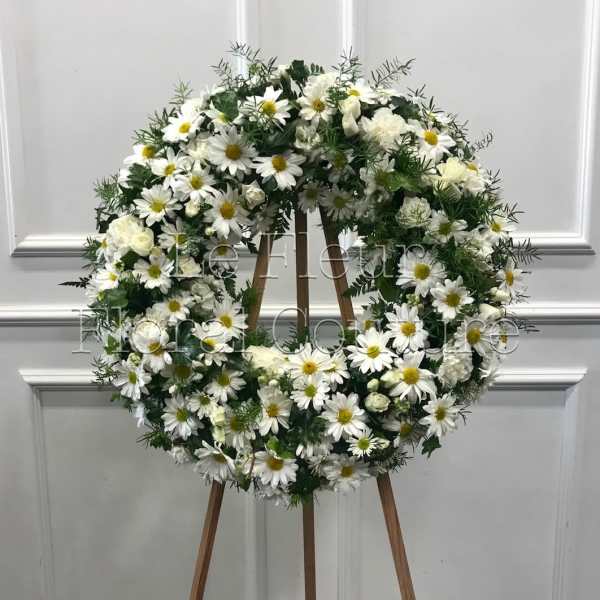 White daisy and rose wreath on a wooden easel
