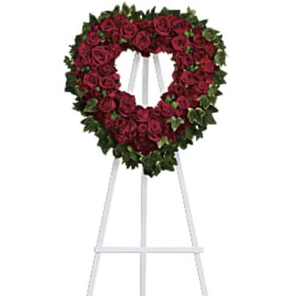 Heart-shaped red rose wreath on a white easel
