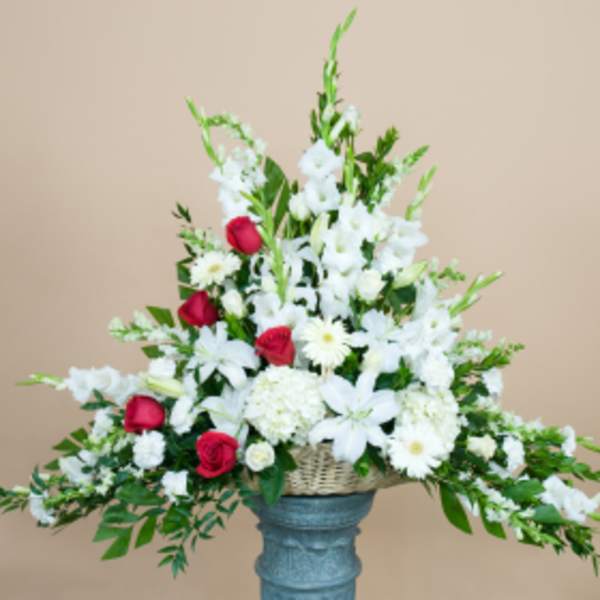 White and red floral arrangement in a basket on a pedestal vase