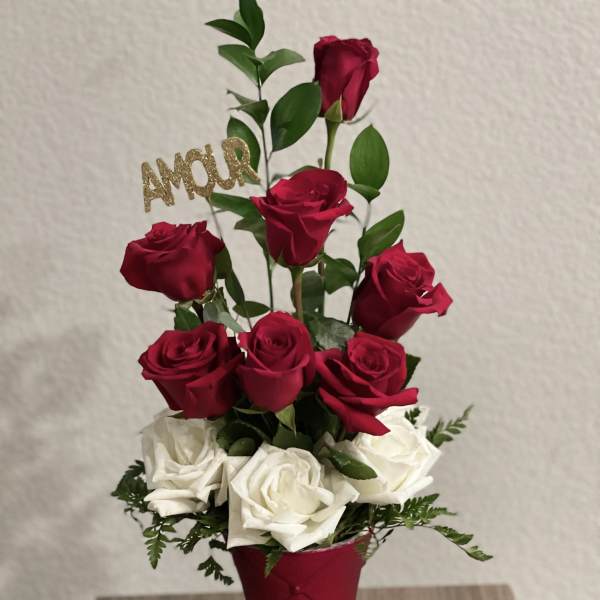 Red and white roses in a red vase with a gold "AMOUR" pick