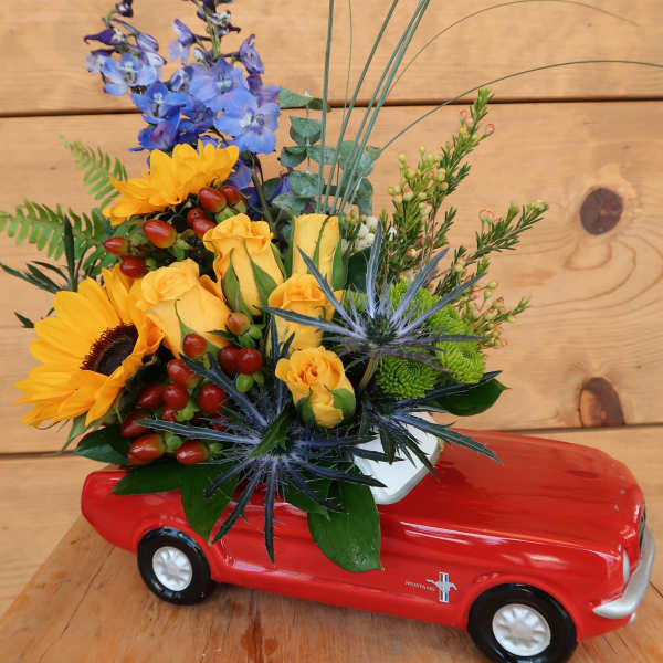 Mixed flower arrangement in a red toy car container
