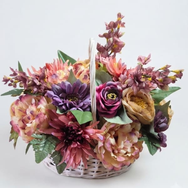 Basket arrangement of multicolored flowers in pink, purple, and peach tones