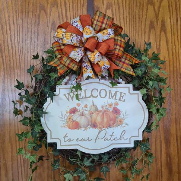 Fall wreath with a pumpkin welcome sign and plaid bow