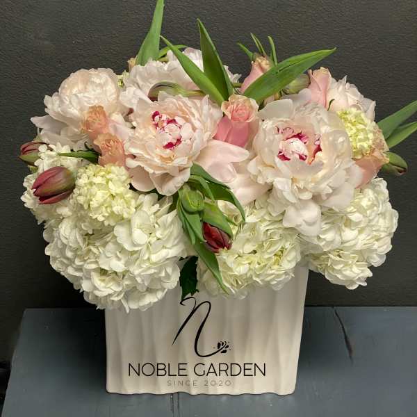 White and blush floral arrangement in a white container