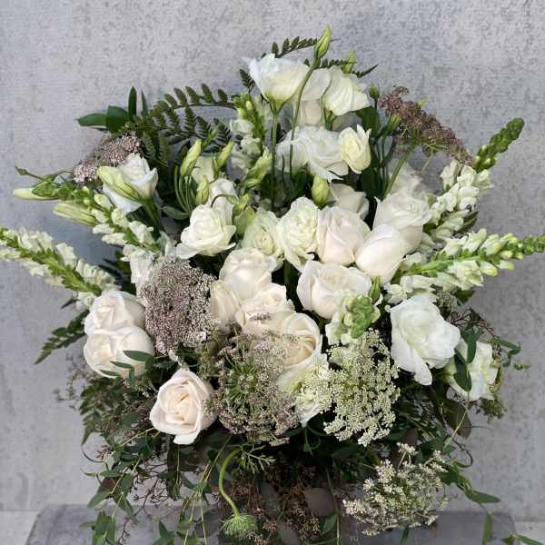 White roses and lisianthus arranged in a dark vase