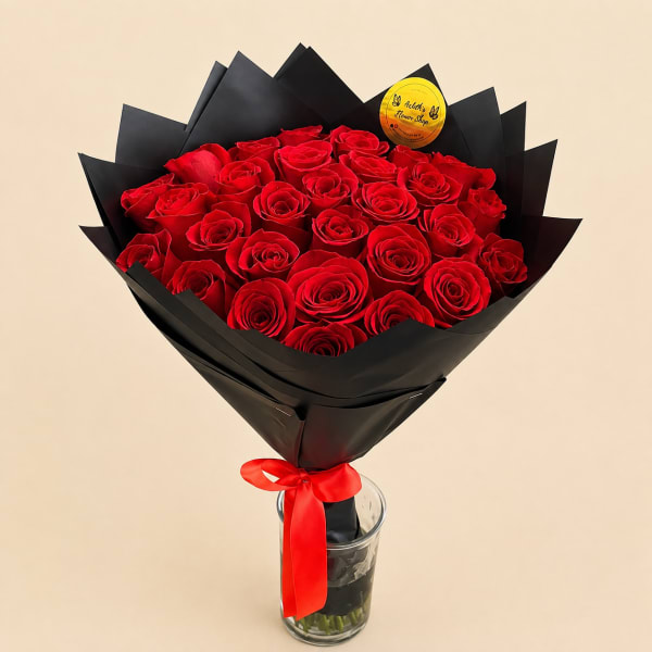 Bouquet of red roses wrapped in black paper with a red ribbon
