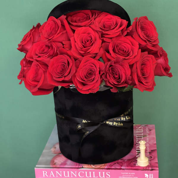 Red roses arranged in a black hatbox with a ribbon