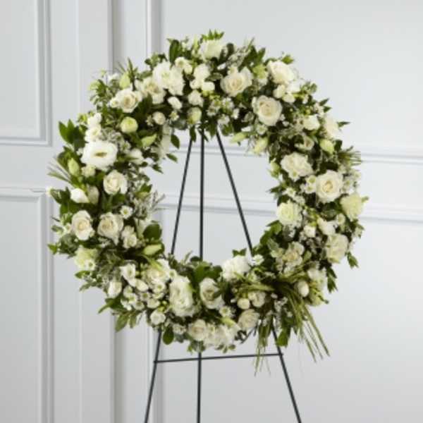 White floral wreath on a black stand