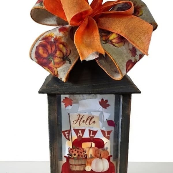 Fall lantern with an orange ribbon bow and autumn-themed insert