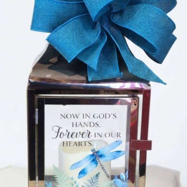 Decorative memorial lantern with a large blue bow and sympathy message