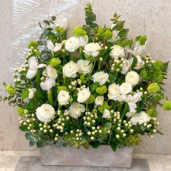 White floral arrangement with green accents in a rectangular container