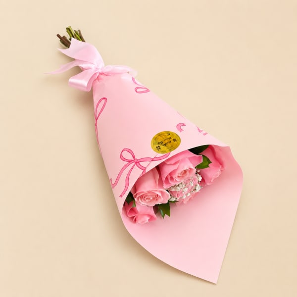 Pink rose bouquet wrapped in pastel pink paper with a satin ribbon