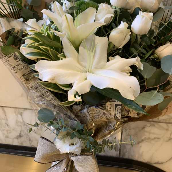 White lilies and roses in a wrapped bouquet with eucalyptus