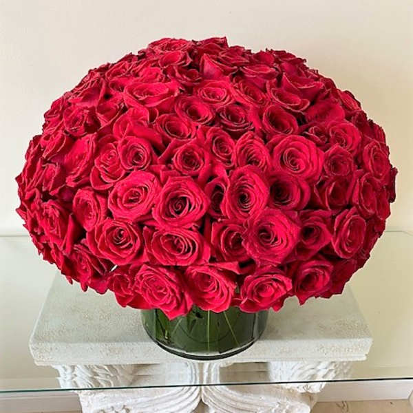 Large dome of tightly packed red roses arranged in a low clear glass vase