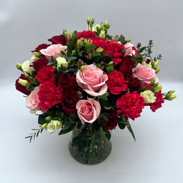Bouquet of pink and red roses and carnations in a glass vase
