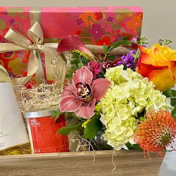 Gift basket with flowers, wine bottle, candle, and ribboned box