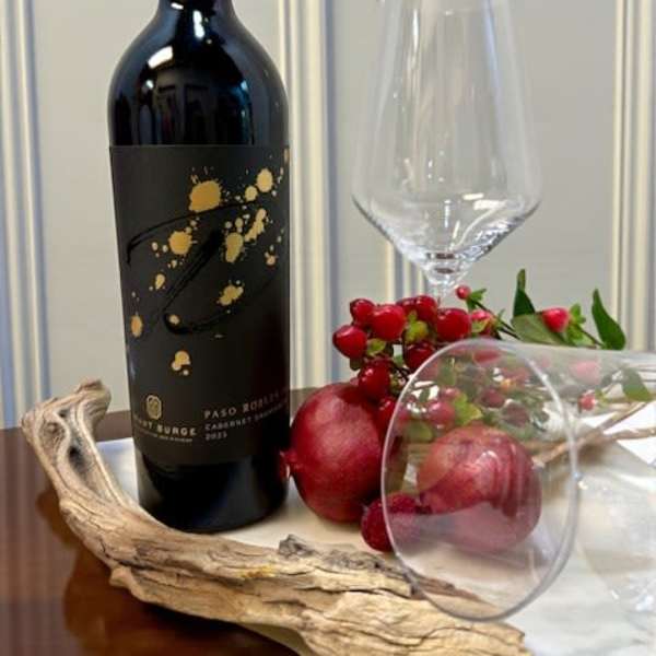 Wine bottle with a clear stemmed glass and red fruit accents