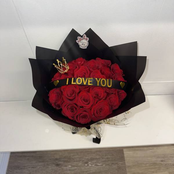 Bouquet of red roses wrapped in black paper with an "I LOVE YOU" ribbon
