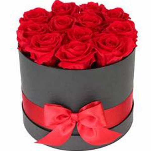 Red roses arranged in a round black box with a red ribbon bow