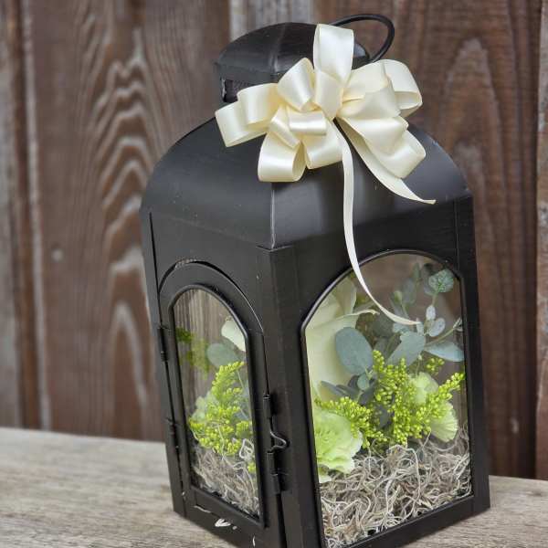 Black lantern with cream ribbon and pale flowers inside