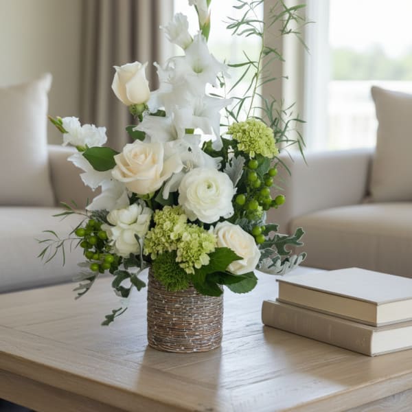 White roses and lilies arranged in a woven vase on a table