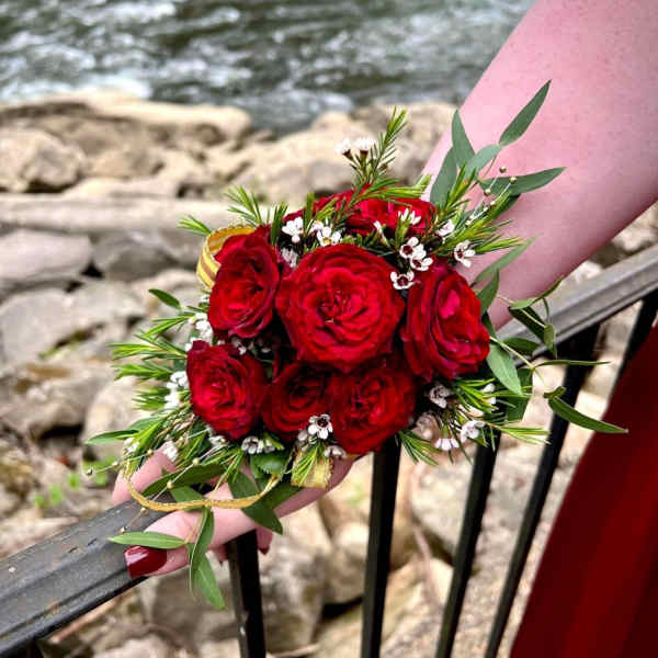 Handheld bouquet of red roses with small white filler flowers