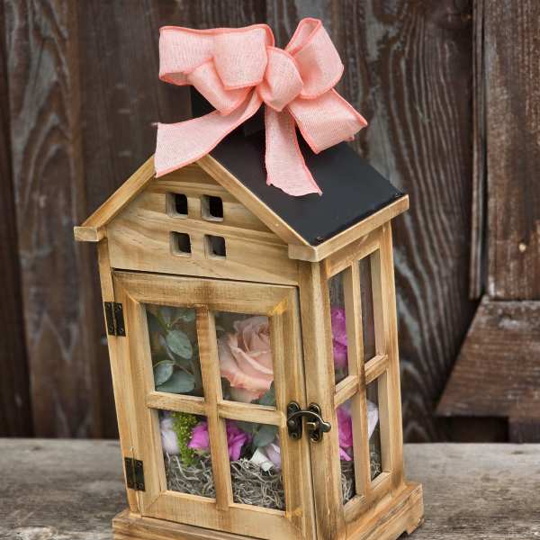 Wooden lantern with pink flowers inside and a pink bow on top