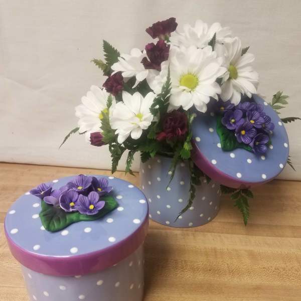 White daisies and purple carnations in a polka-dot box with matching lids