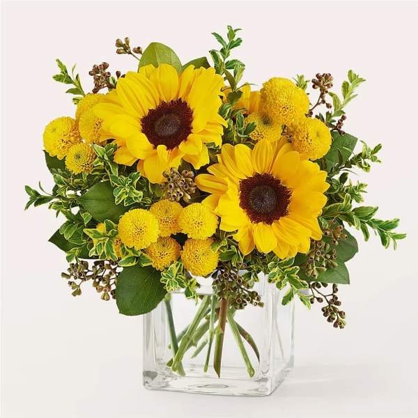 Sunflower and yellow pom bouquet in a clear glass vase