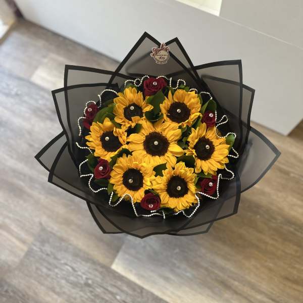 Bouquet of sunflowers and red roses wrapped in black paper