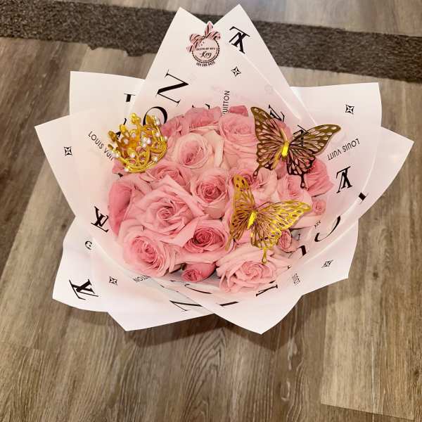 Pink rose bouquet wrapped in white printed paper with butterfly accents